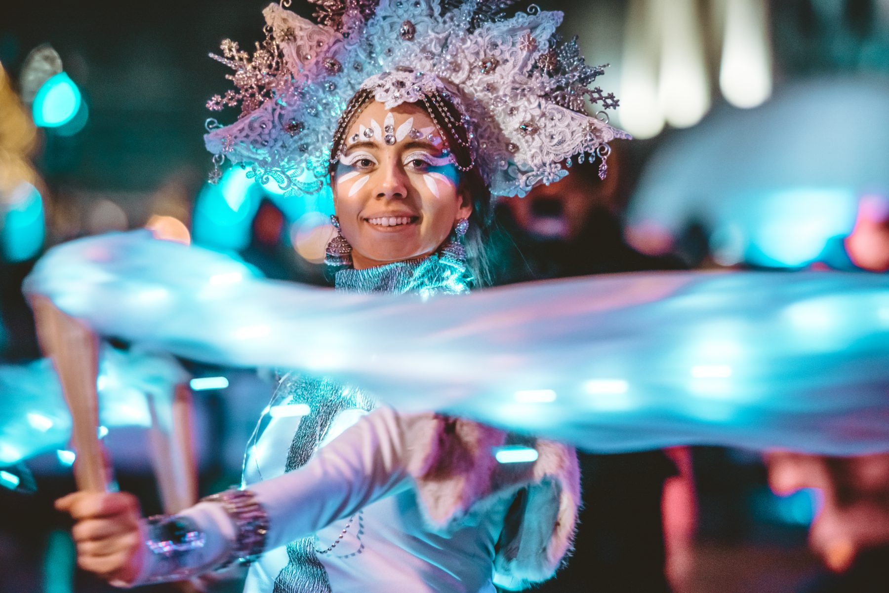 Performer in a winter costume spinning a lit ribbon at Glow Festival