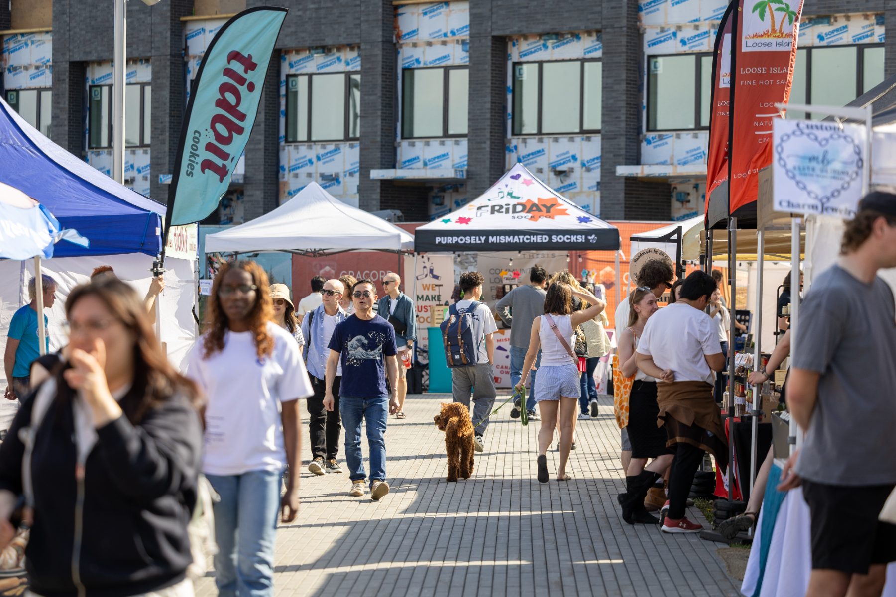 Shoppers filling the market aisle between vendor tents