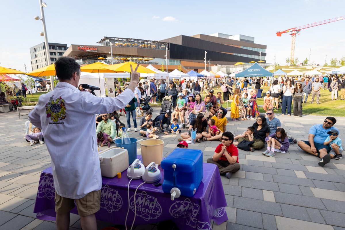 Science demonstration drawing a seated crowd on the lawn