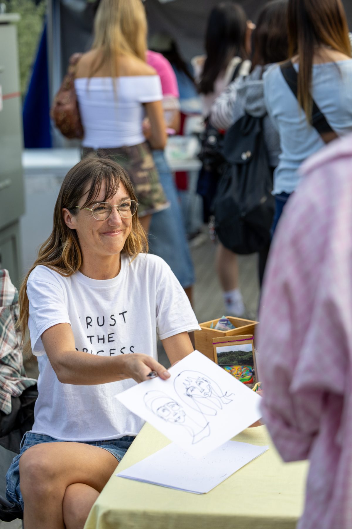 Artist handing over a fresh line drawing at her booth