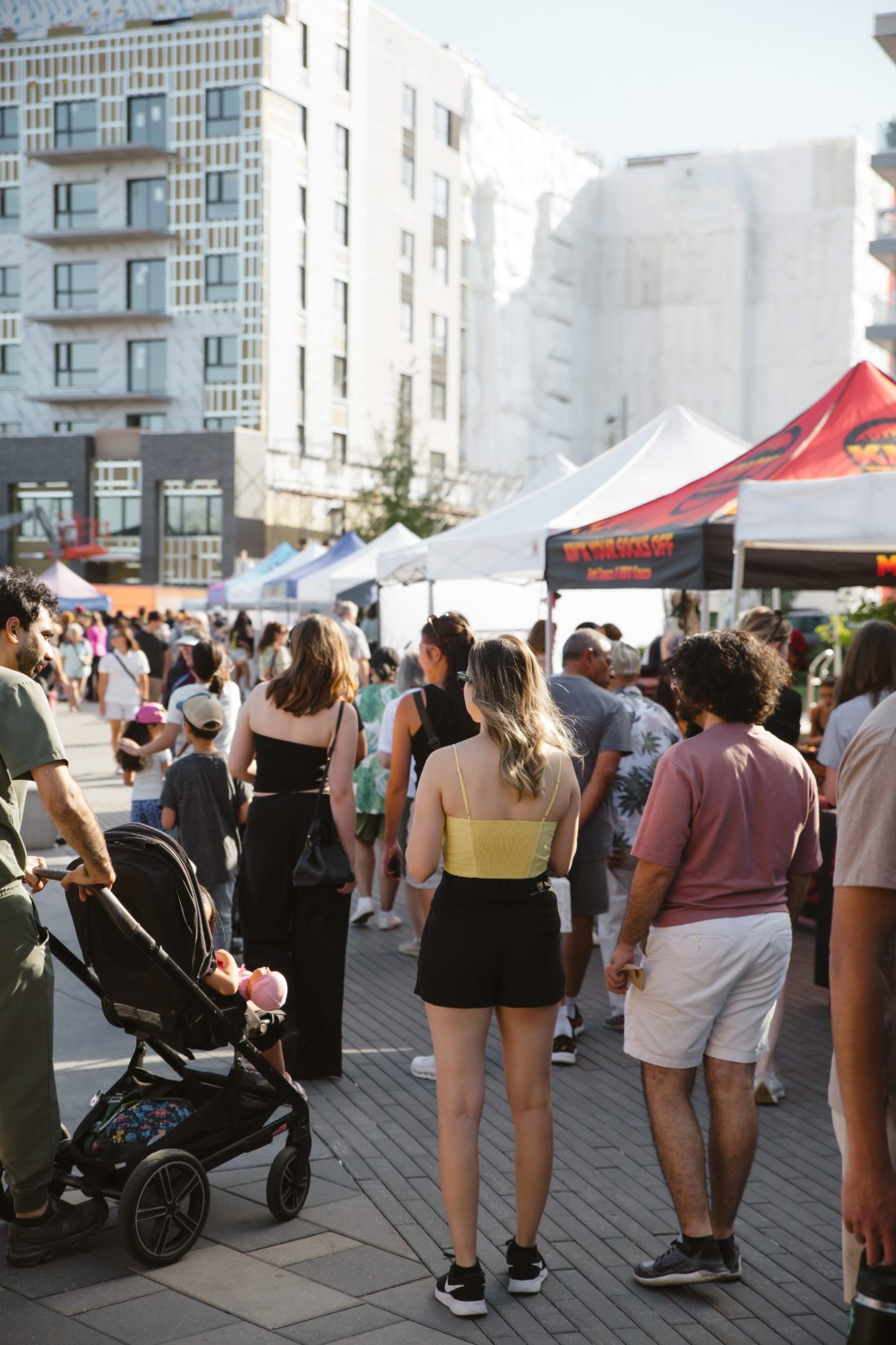 Families and strollers moving through the market at sunset